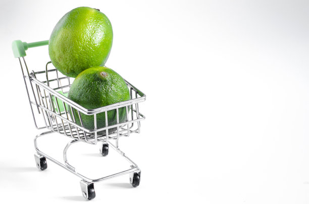在Kopi空间明亮的背景下，一个杂货店篮子里的亮绿色椭圆形酸橙图片下载