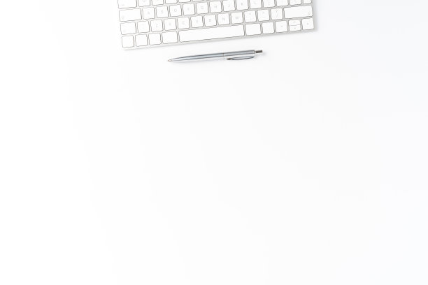 白色桌子上有电脑键盘和笔的办公桌面。极简主义的商业背景图片下载