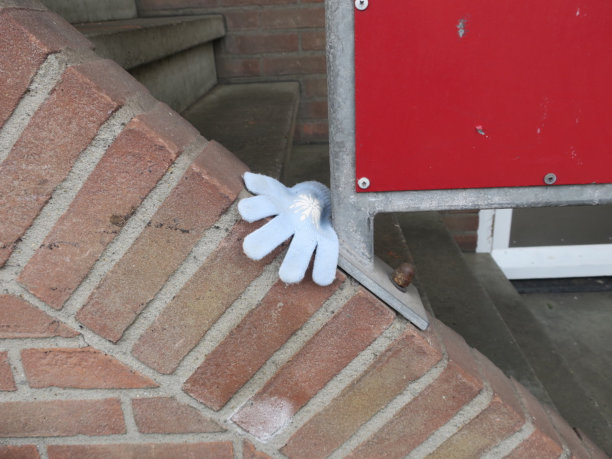 红色砖墙上丢了一只浅蓝色的手套图片下载