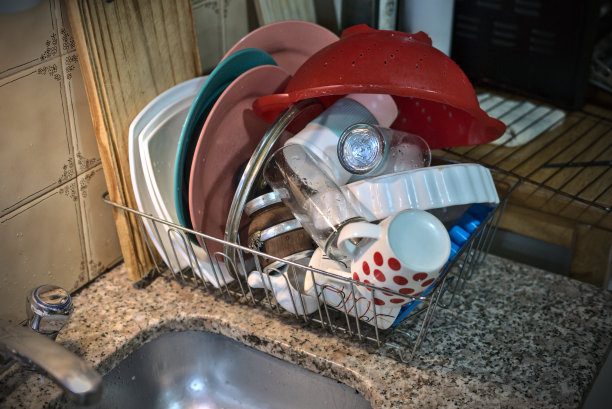 在脏乱的厨房里，刚洗过的盘子放在干衣机上图片下载