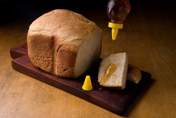 全麦面包放在木板上，切一片，淋上蜂蜜图片下载