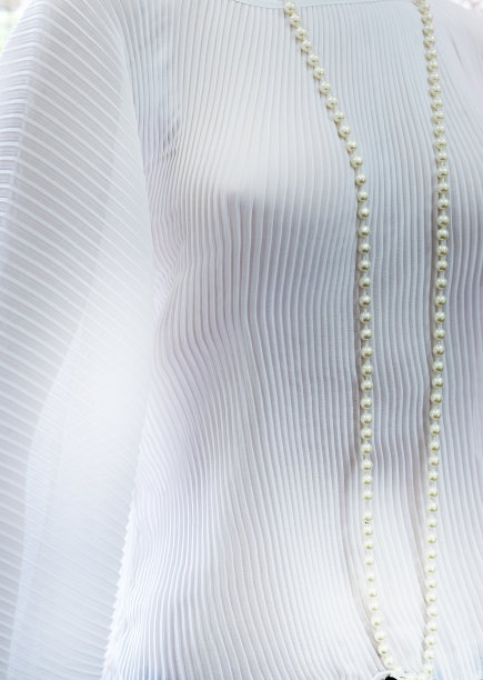 背景从褶皱雪纺透明织物的白色，缝纫，blkza，连衣裙，时尚。白色塑料珠制成的长珍珠项链。图片下载