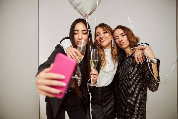 三个有趣的女士用智能手机给自己拍照图片下载