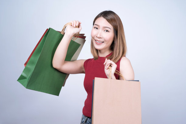 年轻的亚洲女性喜欢购物，在白人背景下与世隔绝。图片下载