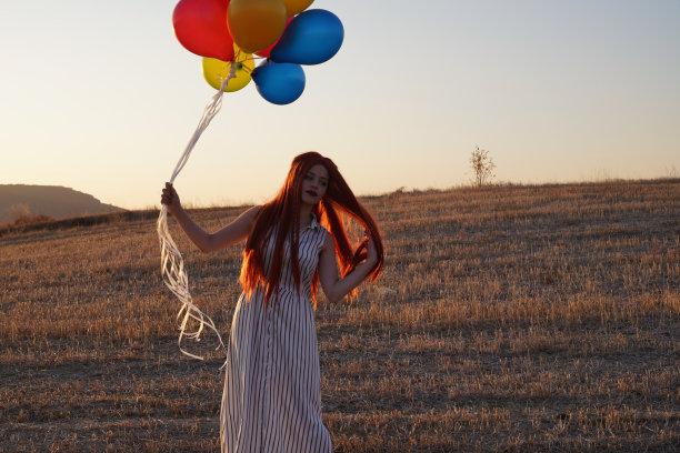 快乐的女人与气球在日落在夏季股票照片图片下载