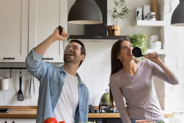 快乐的年轻家庭夫妇有乐趣唱歌在家里厨房图片下载