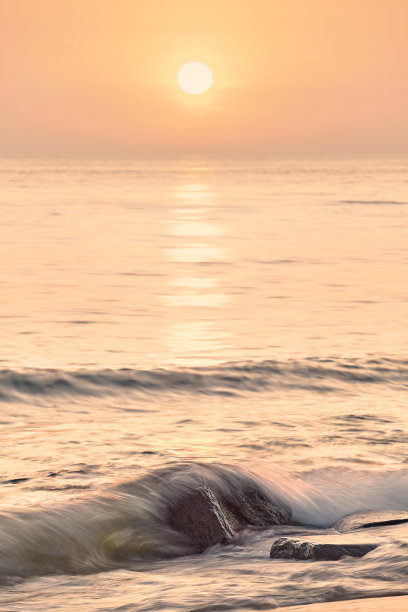 宁静的沙滩日出，选择性聚焦于岩石，长时间曝光照片。图片下载