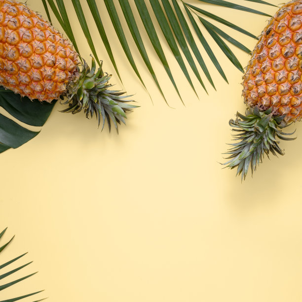 俯视图的新鲜菠萝与热带树叶在黄色的背景。图片下载