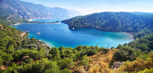 从山上看到土耳其Fethiye附近的Oludeniz泻湖的蓝色水面。地中海沿岸树木丛生，天空晴朗素材图片