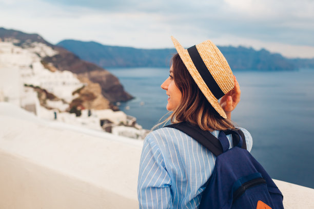 一名女游客走在希腊圣托里尼岛上欣赏海景。游客在伊亚欣赏火山口的景色图片下载