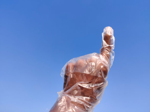 印度南部男性手戴一次性塑料手套，做出第一手势。云背景图片下载