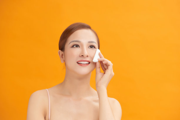 美丽的女人卸妆用棉花圆在一个白色的背景图片下载