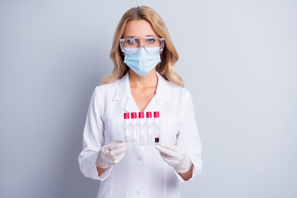 照片的成熟的化学家妇女在护目镜和面罩持试管与流体内隔离在灰色背景图片下载