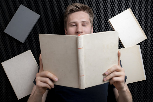 俯视图的一个男孩少年躺在地板上看书，学习和研究图片下载