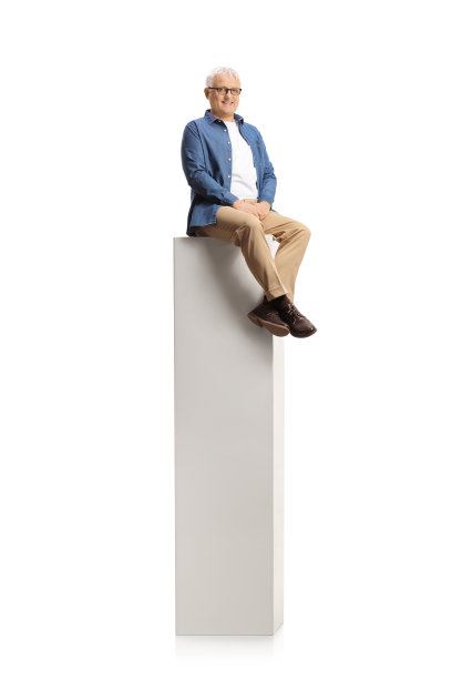 微笑的成熟男子坐在一个高大的白色柱子上，对着镜头微笑图片下载