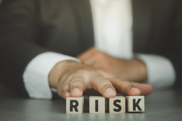 商人的风险评估。决定接受业务造成的不确定性、不可预测的情况概念。用手推立方体木块，用字母构建单词RISK图片下载