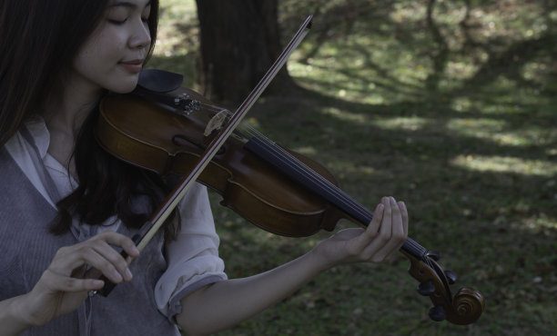 年轻美丽的女士手拿小提琴，展示如何弹奏原声乐器，图片下载