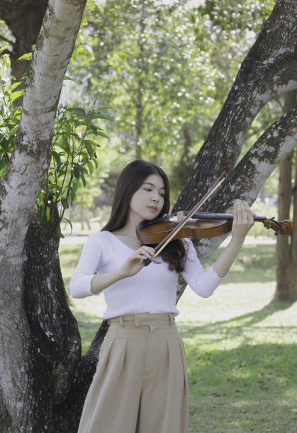 年轻美丽的女士手拿小提琴，展示如何弹奏原声乐器，图片下载