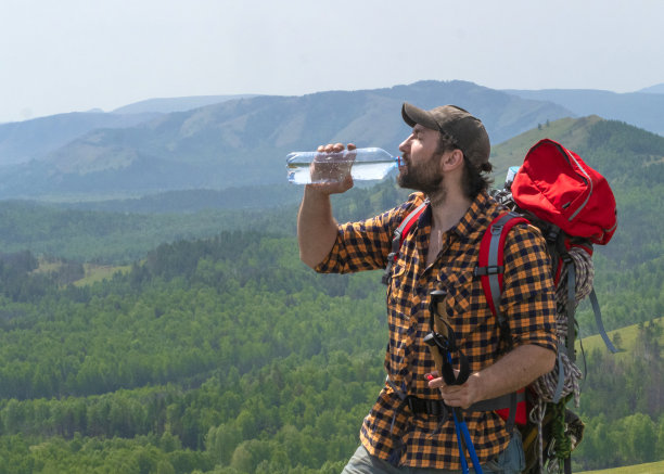 山里的中年徒步旅行者。一个人在山里旅行时用一个塑料瓶喝水图片下载