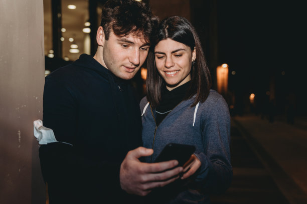 一对年轻的成年夫妇在锻炼过程中休息一下，看看智能手机图片下载