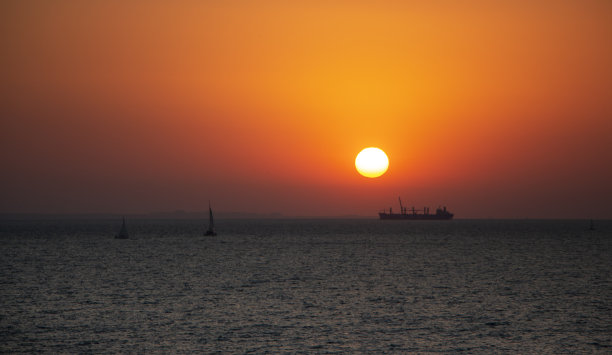 海上红色的日出天空和海上船只的剪影。图片下载