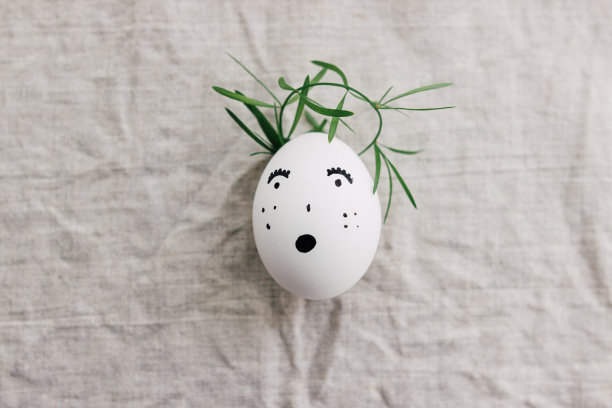 复活节彩蛋与画惊讶的脸在可爱的花皇冠上亚麻织物。俯视图图片下载