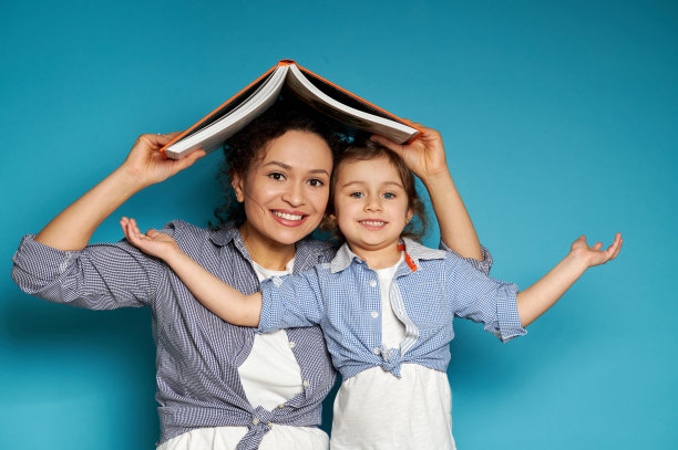 母女俩对着镜头开心地笑着，把一本书举过头顶，那是房子的屋顶图片下载