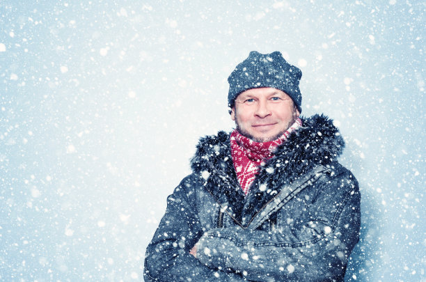 快乐微笑的大胡子穿着冬装，周围是下雪的背景。图片下载