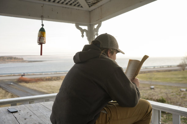 一个孩子在俯瞰大海的门廊上看书。图片下载