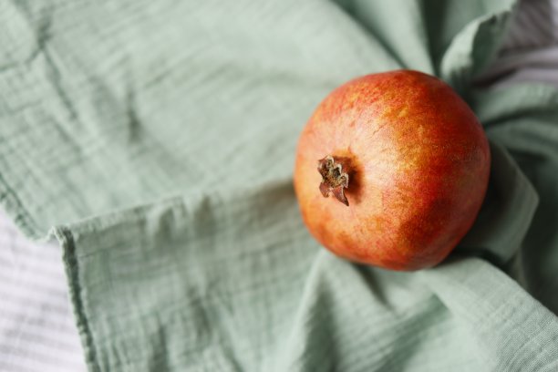 一个黄橙红的石榴在绿色的亚麻布上，侧视图图片下载