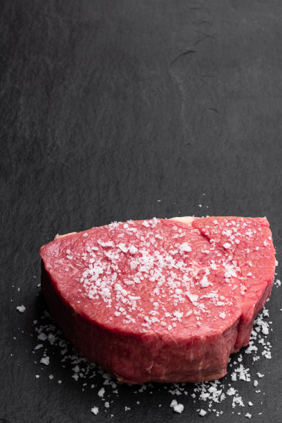 新鲜和生牛肉与海盐在黑色的石头背景图片下载