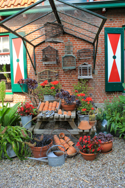 在花园的一个角落里，有天竺葵和喷壶，在有鸟笼的墙前的野餐长凳上图片下载