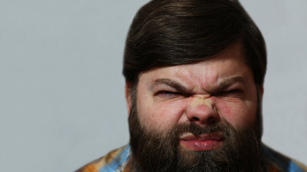 肖像。灰色背景上一个满腹牢骚的大胡子男人。图片下载