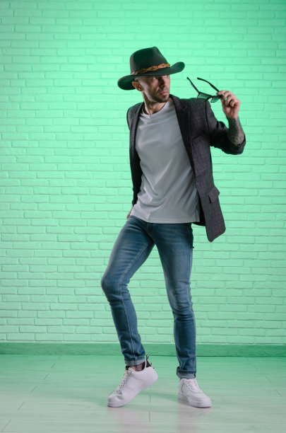 一名穿着夹克、头戴牛仔帽的时尚男子在摄影棚摆造型图片下载