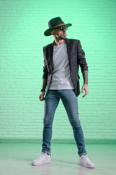 一名穿着夹克、头戴牛仔帽的时尚男子在演播室摆姿势图片下载