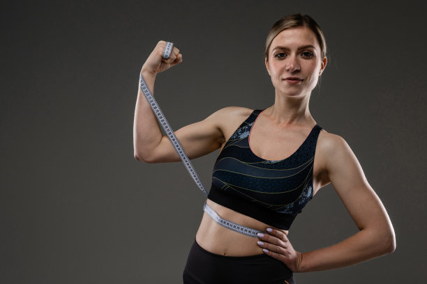 运动白人女孩与苗条的身材做运动与运动磁带隔离在黑色的背景图片下载