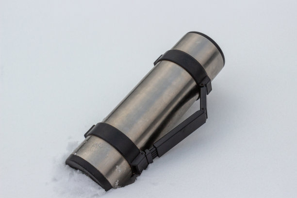 热水瓶放在白雪上图片下载