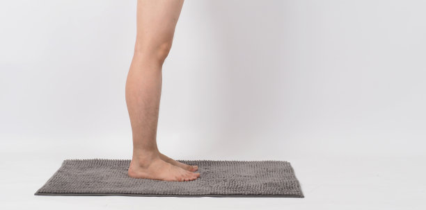 赤脚行走在柔软地毯上的男性的双腿。白色背景。隔离和复制空间图片下载