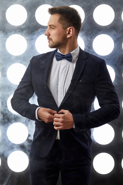 穿着燕尾服的英俊男子在聚光灯的背景下摆姿势图片下载
