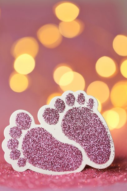 新生儿的名片。一个女孩的出生。粉红色的闪光宝宝的脚在粉红色的闪光背景与黄色的闪光散焦。婴儿的邀请。出生公告。文本空间图片下载