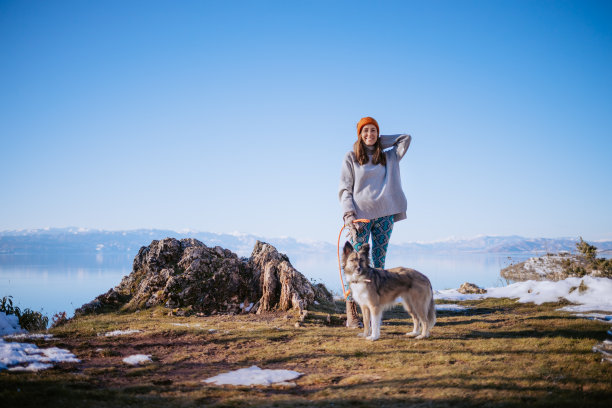 一个女人在冬天的湖边遛狗的照片图片下载