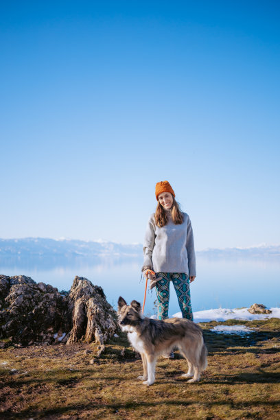 一个女人在冬天的湖边遛狗的照片图片下载