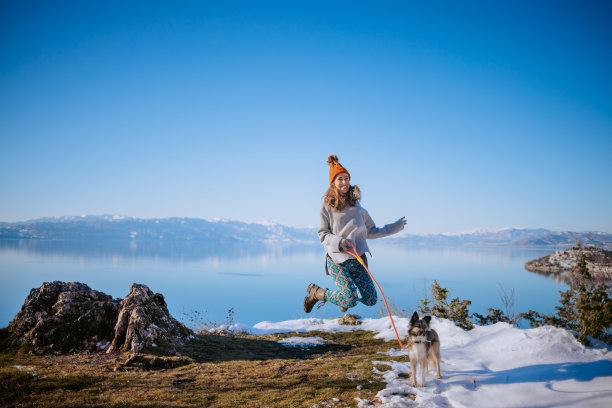 一个女人在冬天的湖边遛狗的照片图片下载