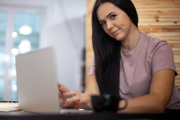 专注的年轻女子一边在办公室里喝咖啡，一边在电脑上打字图片下载