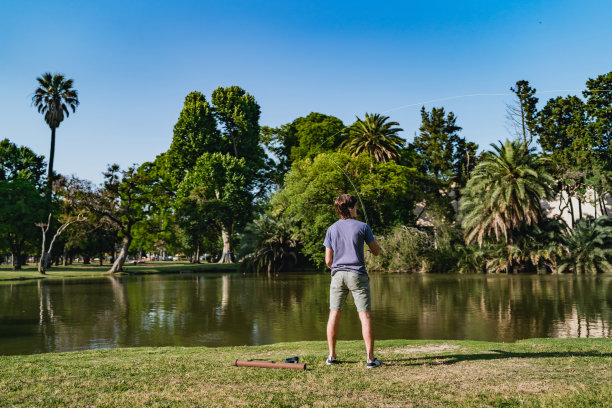 少年在公园的湖里钓鱼图片下载