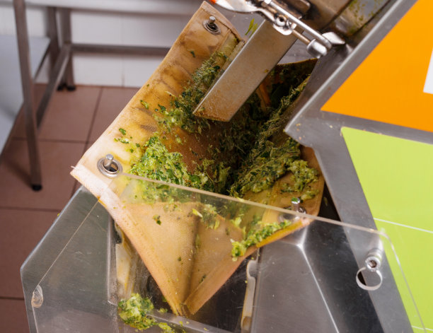 绿色冷榨果汁工艺在工业厨房的照片。图片下载