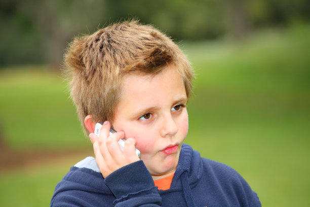 公园里漂亮的红男孩正在用移动电话说话图片下载