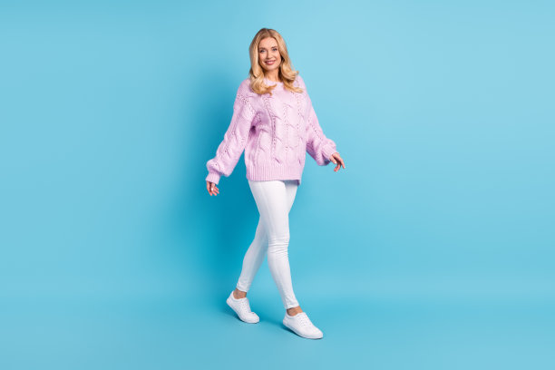 完整的身体尺寸照片美丽的女人微笑着向前走在休闲服装孤立在生动的蓝色背景图片下载