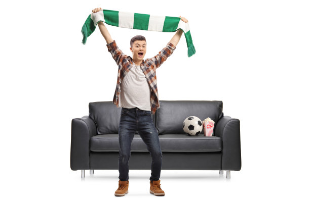 一名男性少年的全身像，他戴着围巾站在沙发前，手里拿着一个足球和爆米花欢呼图片下载