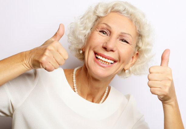 年长的妇女竖起大拇指，看着镜头图片下载